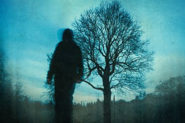 Ürkütücü bir hayalet figürü. Kameraya doğru yürüyorum. Kasvetli bir kış günü kırsalda. Bir grunge düzenleme ile.