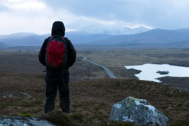 Bir dağda duran bir yürüyüşçü, soğuk kış manzarasına bakıyor. Outer Hebrides, İskoçya, İngiltere