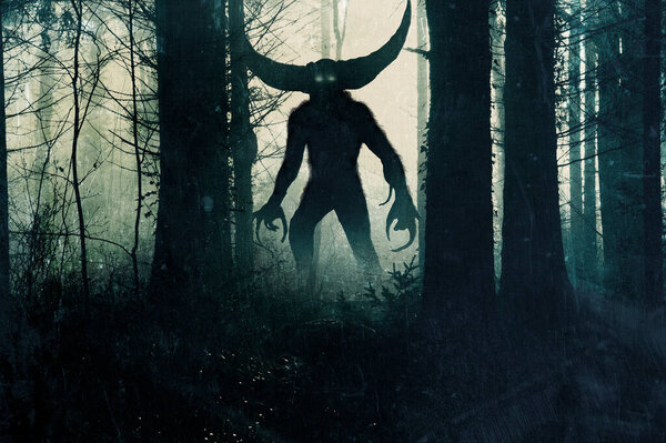 A horror demonic monster. With glowing eyes and horns. Silhouetted in a dark, foggy winter forest. 