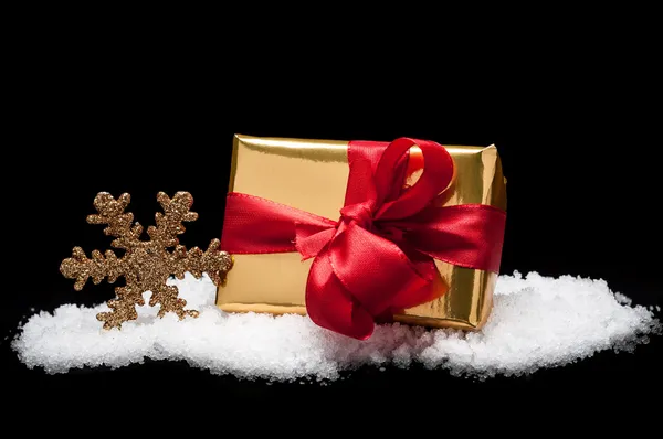 Golden christmas gift in snow — Stock Photo, Image