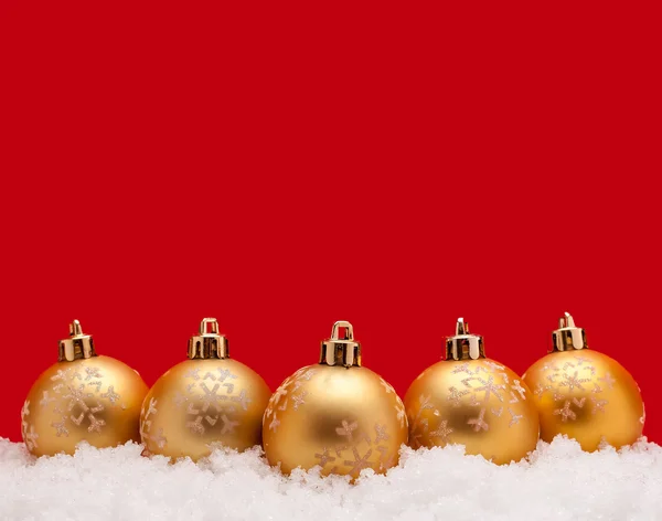 Gold christmas balls with snow isolated on red bacground Stock Photo