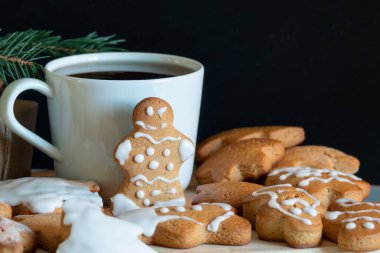 Zencefilli bisküvilerden gelen zencefilli çörekler siyah arka planda şeker kreması süslemesi, asgari mevsimlik kış bayramı afişi.