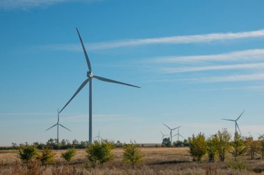 Rüzgâr türbinleri açık arazide rüzgarlı günlerde gökyüzünde kara bulutlarla birlikte eserler. Alternatif güç üretimi. Boşluğu kopyala.