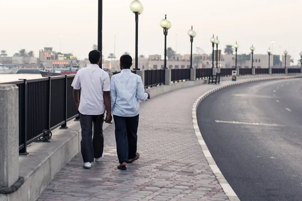 Two friends walking on the embankment at the river in Dubai — Stock Photo, Image