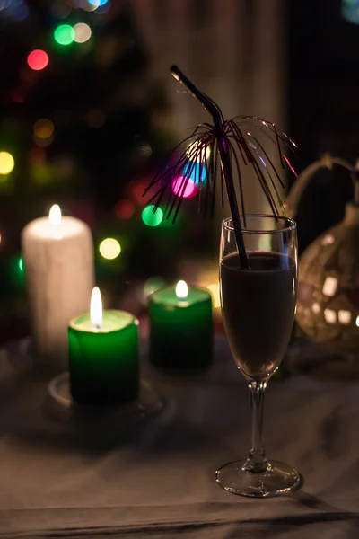 Een glas champaigne met kaarsen en kerstboom aan de achterkant — Stockfoto