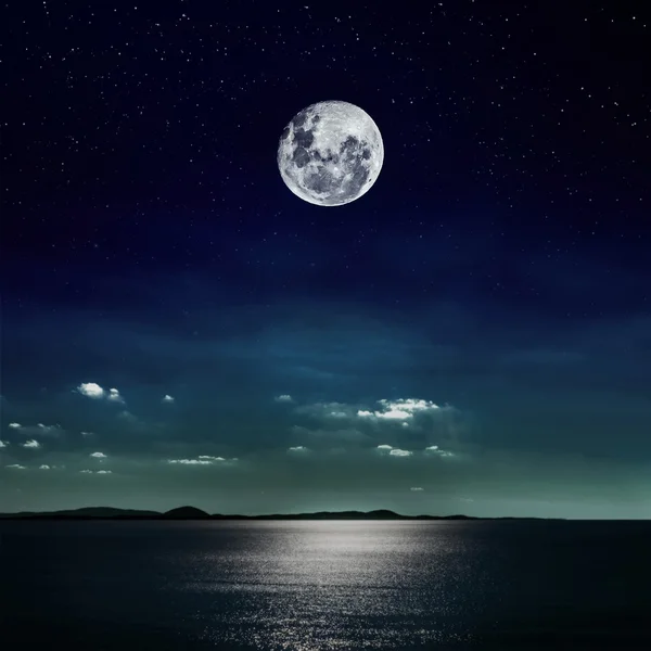 Luna piena riflessa sulla spiaggia Immagine Stock