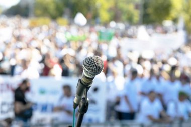 Protesto ya da halk gösterileri, mikrofona odaklanma, arka planda bulanık insan kalabalığı