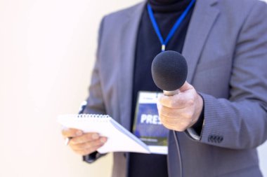 Medya röportajı yapan bir muhabir mikrofon tutuyor