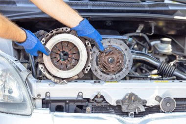 Kullanılmış basınçlı plaka ve araç motoru önünde debriyaj diski tutan oto tamircisi