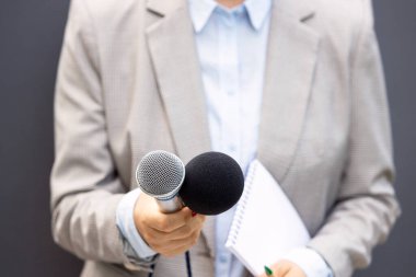 Basın konferansında ya da medya etkinliğinde kadın gazeteci, notlar yazma, mikrofon tutma