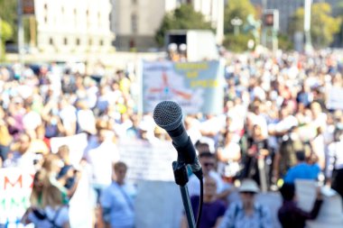 Protesto ya da halk gösterileri, mikrofona odaklanma, arka planda bulanık insan kalabalığı