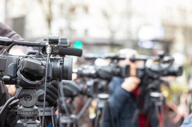 Haber ya da basın toplantısı. Bir video kamera ile ortam olayı kaydediliyor.