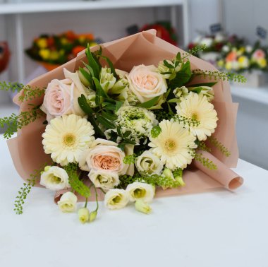 Çiçek aranjmanı masada. Dekoratif çiçek süslemesi. Çiçekçi. Rengarenk çiçeklerden oluşan güzel bir buket. Çiçekçiden çiçek teslimatı. Sevgililer Günü