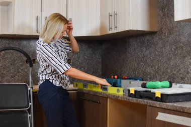 Evde genç bir inşaatçı kadın var. Kız ev hanımı dairede onarım yapıyor. Ev işlerinde yardım. İnşaat aletli kadın