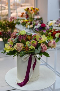 Çiçek aranjmanı masada. Dekoratif çiçek süslemesi. Çiçekçi. Rengarenk çiçeklerden oluşan güzel bir buket. Çiçekçiden çiçek teslimatı. Sevgililer Günü