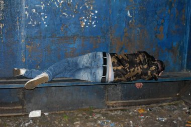 Sarhoş adam otobüs durağındaki bankta uyuyor. Evsiz bir adam eski bir bankta yatıyor. Evsizlere ve işsizlere sosyal yardım