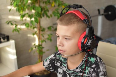 Kulaklıklı bir çocuk bilgisayar başında oturmuş oyun oynuyor. Çocuk oyuncağı bağımlılığı