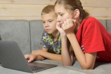 Çocuklar evdeki kanepede yatarken dizüstü bilgisayara bakıyorlar. Uzaktan kumandalı internet eğitiminde olan kardeşler. Çocuklar arkadaşlarıyla çevrimiçi sohbet eder