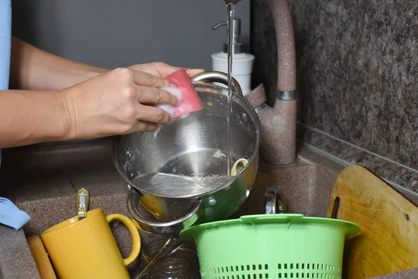 女は台所の洗面台で食器を洗う 主婦は家庭で汚れた食器を洗い — ストック写真