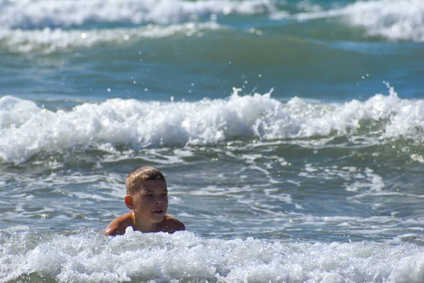 소년은 파도를 바다에서 수영한다 아이는 휴가중 바다에서 활발하게 휴식을 취하고 — 스톡 사진