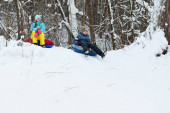 happy kids tubing down snow slide in winter. cheerful childrens active sports winter recreation. ice mountain skiing
