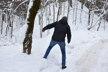 snow falls from a tree in the forest on a man. man falls on a snowy road. man will run away from an avalanche