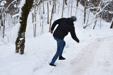 snow falls from a tree in the forest on a man. man falls on a snowy road. man will run away from an avalanche