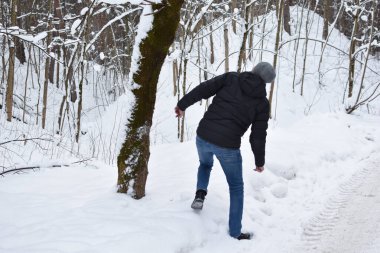 snow falls from a tree in the forest on a man. man falls on a snowy road. man will run away from an avalanche