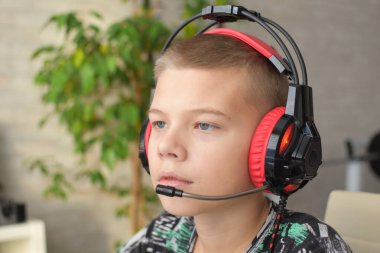 a boy with headphones sits at a computer playing online games. children's gambling addiction.
