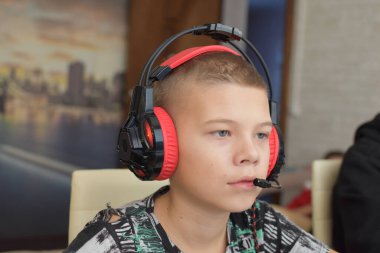 a boy with headphones sits at a computer playing online games. children's gambling addiction.
