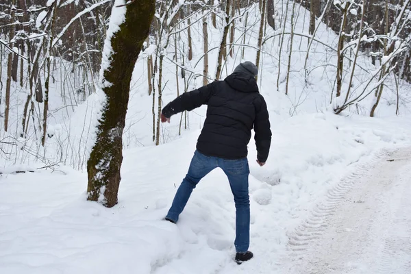snow falls from a tree in the forest on a man. man falls on a snowy road. man will run away from an avalanche