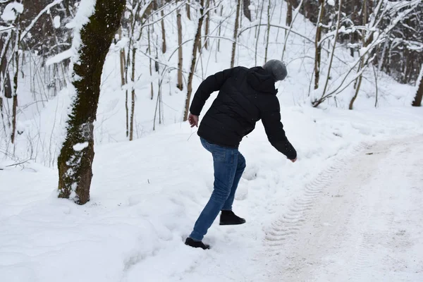 snow falls from a tree in the forest on a man. man falls on a snowy road. man will run away from an avalanche