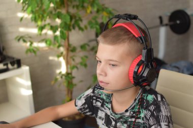 Caucasian boy in red headphones is trained at home at the computer. child playing online game