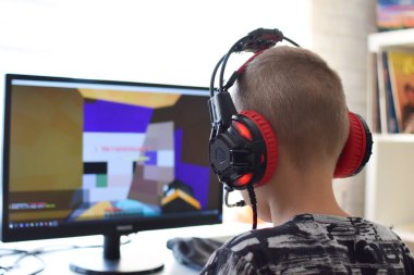 Caucasian boy in red headphones is trained at home at the computer. child playing online game