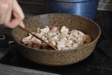 cooking meat in a pan on the stove in the kitchen. a piece of meat is fried in a skillet