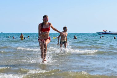 a slender beautiful girl teenager in a swimsuit runs along the seashore. fun vacation by the sea