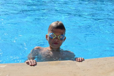 cheerful happy boy child swim in swimming pool in summer outside. tourist swimming season for children at sea