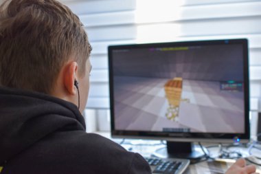 boy looks into a computer monitor. the child plays online games. distance learning of children