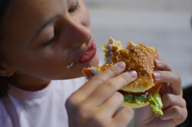 girl eating delicious fast food hamburger with fries.