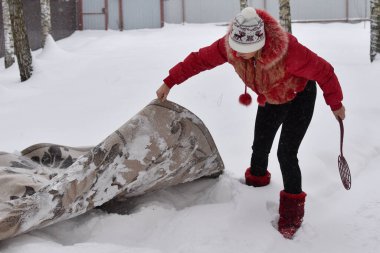 beat the carpet from dust in the winter in the snow. cleaning home carpets with snow. the carpet lies on white snow