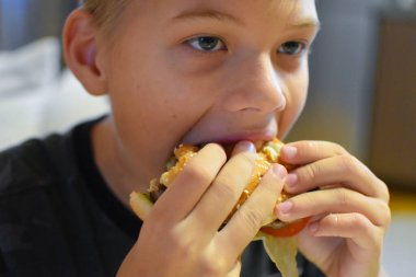 boy eating delicious fast food hamburger with fries.