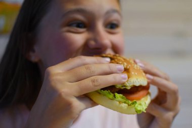 girl eating delicious fast food hamburger with fries.