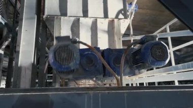 İki mavi indüksiyon motoru endüstriyel bir fabrikada çalışıyor. Bir tanesi gevşek, kötü tamir edilmiş..