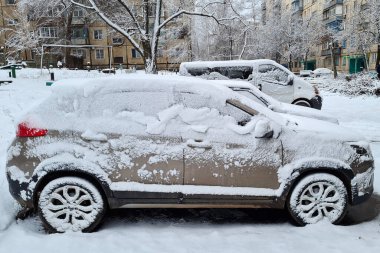 Kar fırtınası altında gri SUV aracının yakın plan görüntüsü. Soğuk kış karlı arka plan.