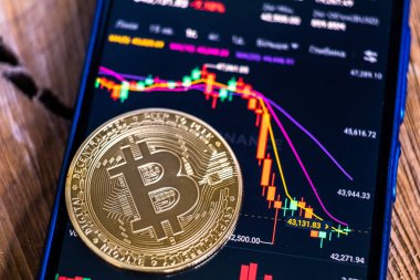 Şifreleme piyasasının Binance borsasında düşüşünün grafiği olan bir akıllı telefon ekranının arka planında bitcoin para var. Ayı pazarı konsepti. KRYVYI RIH, UKRAINE - HAZİRAN 06, 2022