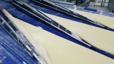 Hareket eden bir taşıyıcı banttaki hamur tabakası kesilir ve lezzetli çörekler yapmak için hazırlanır. Modern Endüstriyel Fırın Malzemeleri.