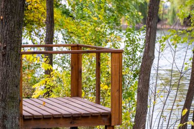 Şehir parkındaki boş ahşap iskele sonbahar günü gölün arka planında, kimse yok..