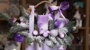 Christmas composition. Wooden wicker with branch of the Christmas tree, purple Christmas toys, balls, candle rotate in a circle.