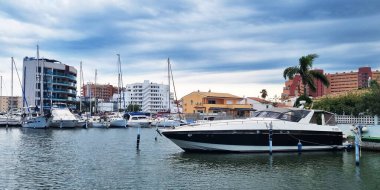 Küçük beyaz yatlar, şehir binaları arasındaki kanalda. Şehir kanalında kiralık tekneler. Güller, KATALONYA, İspanya - Ağustos, 2022