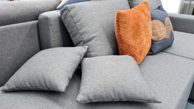 Gri ve turuncu yastıklar lüks bir evde modern bir kanepede..